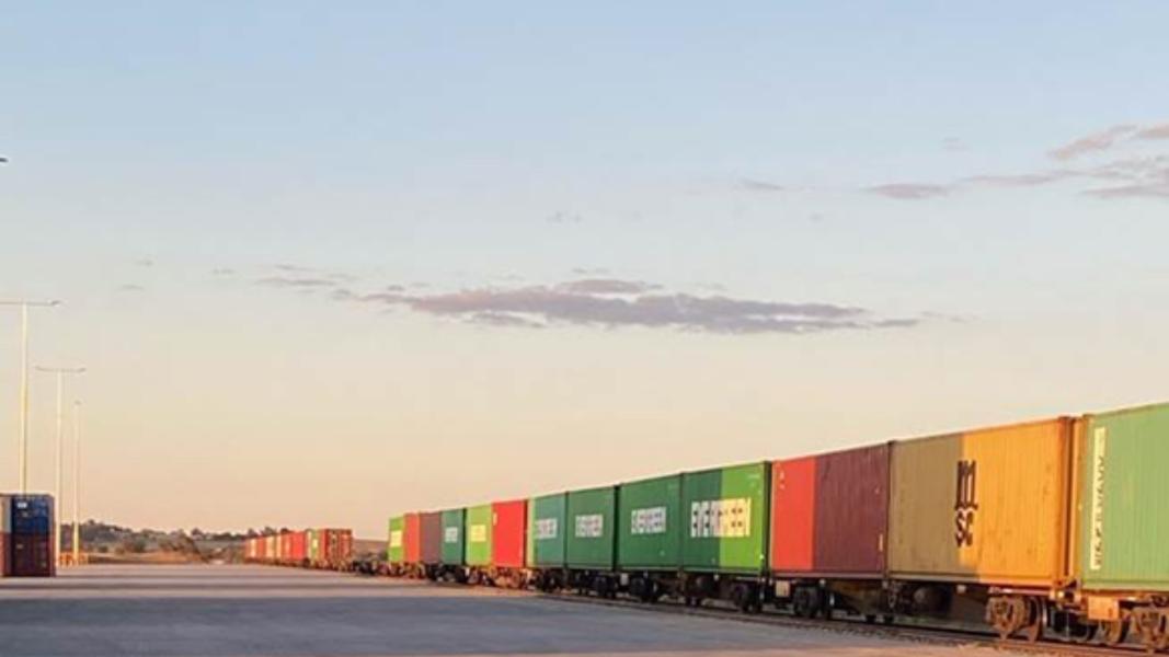 A long train with lots of different coloured containers on it
