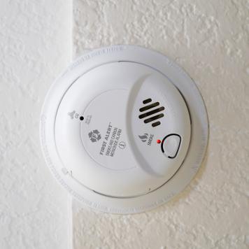 A smoke alarm attached to a white ceiling